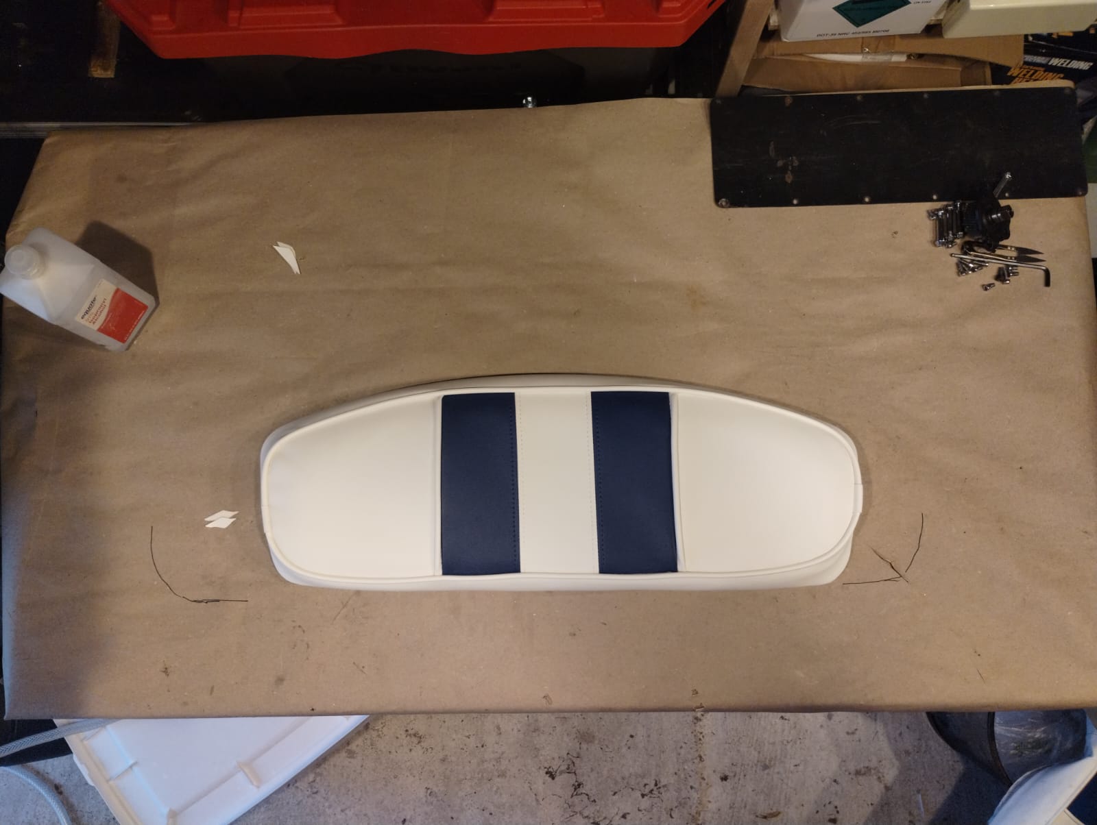 Finished curved boat bolster cushion in white marine vinyl with navy blue stripe