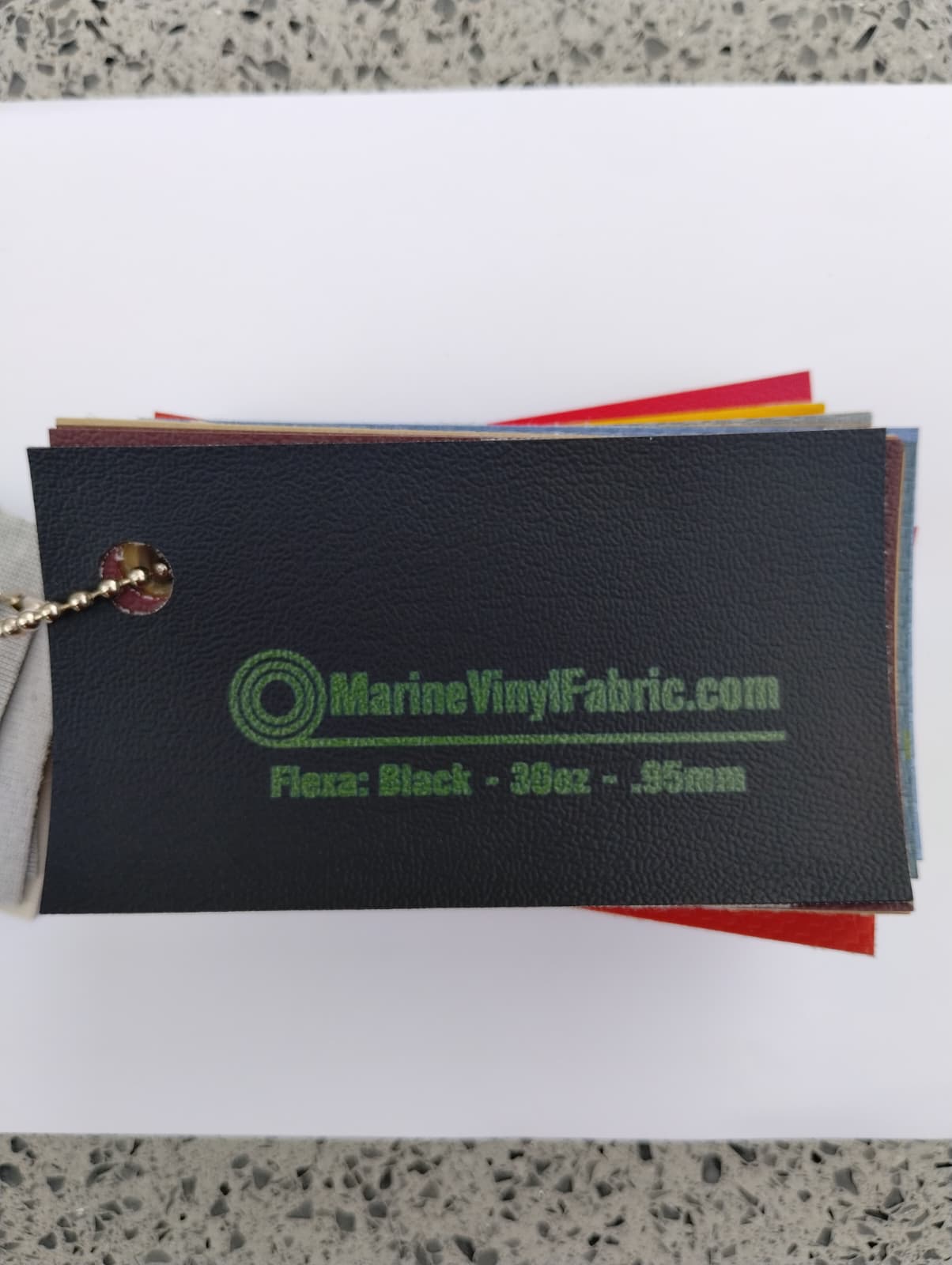 Black Flexa marine vinyl upholstery fabric swatch on a sample ring, 30oz and 0.95mm marine grade
