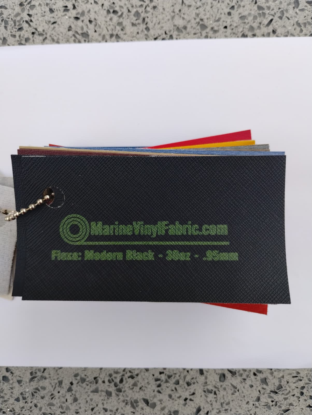 Black cross hatch textured Flexa marine vinyl upholstery fabric swatch on a sample ring, 30oz and 0.95mm marine grade