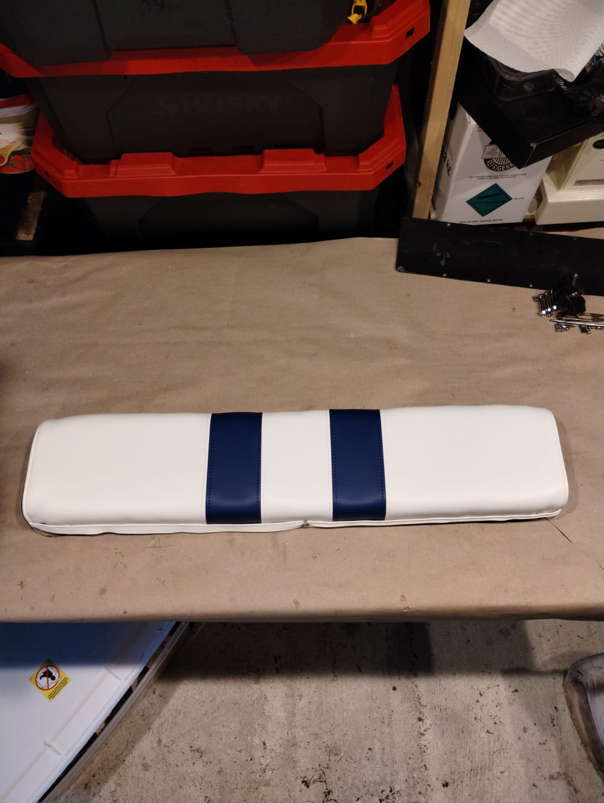 Finished boat bench seat cushion reupholstered in white marine vinyl with navy blue stripes