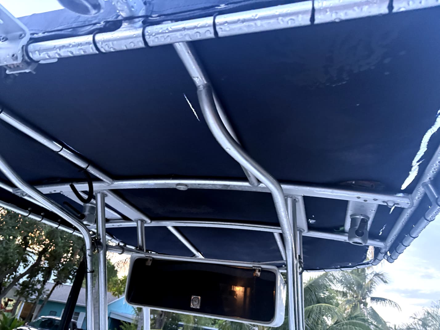 Underside view of worn navy boat T-top canvas showing a tear near the frame support