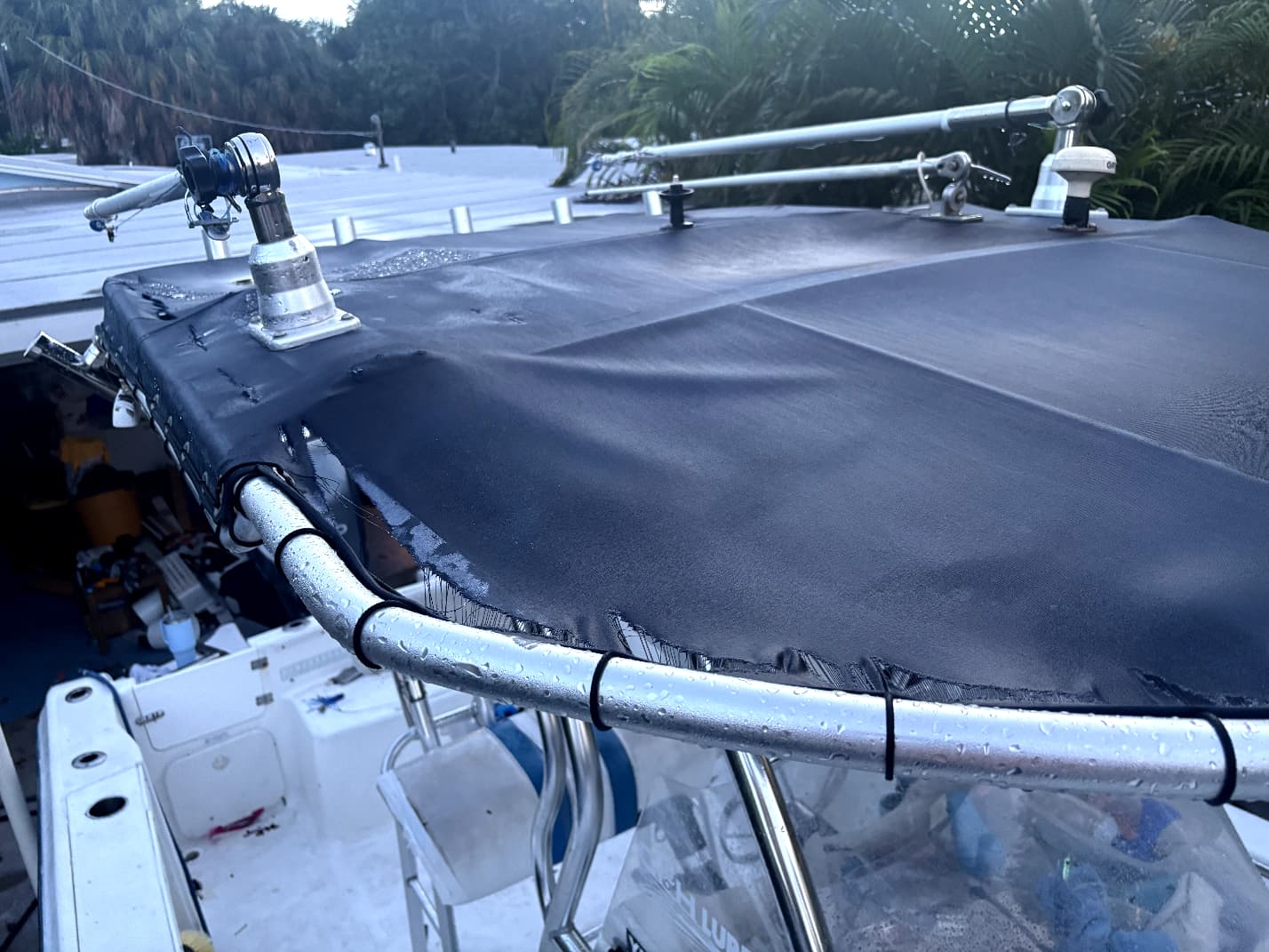 Worn black boat T-top canvas sagging with a split edge pulling away from the frame before replacement
