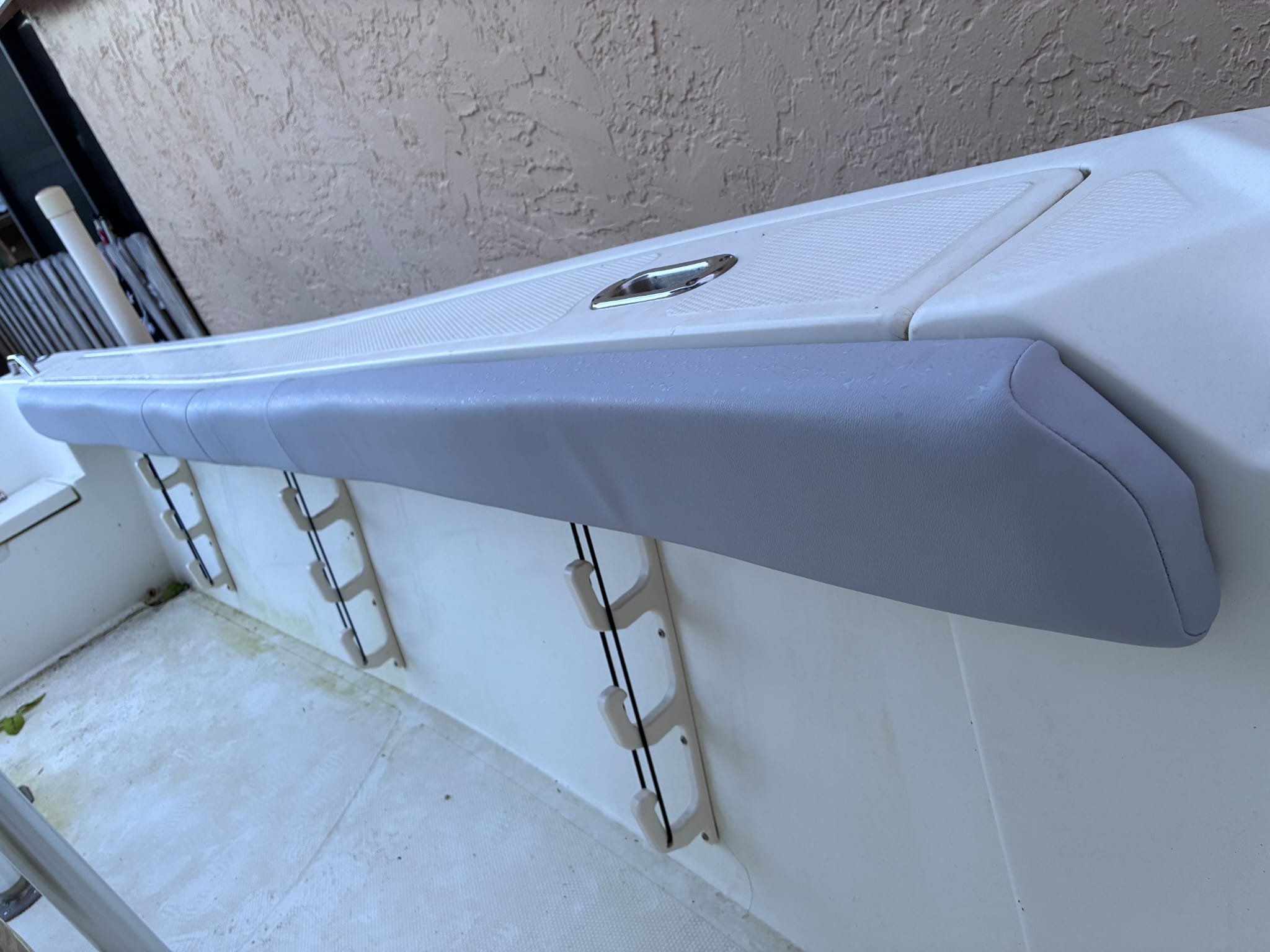 A newly upholstered gray marine vinyl bolster cushion along a boat's gunwale rail.