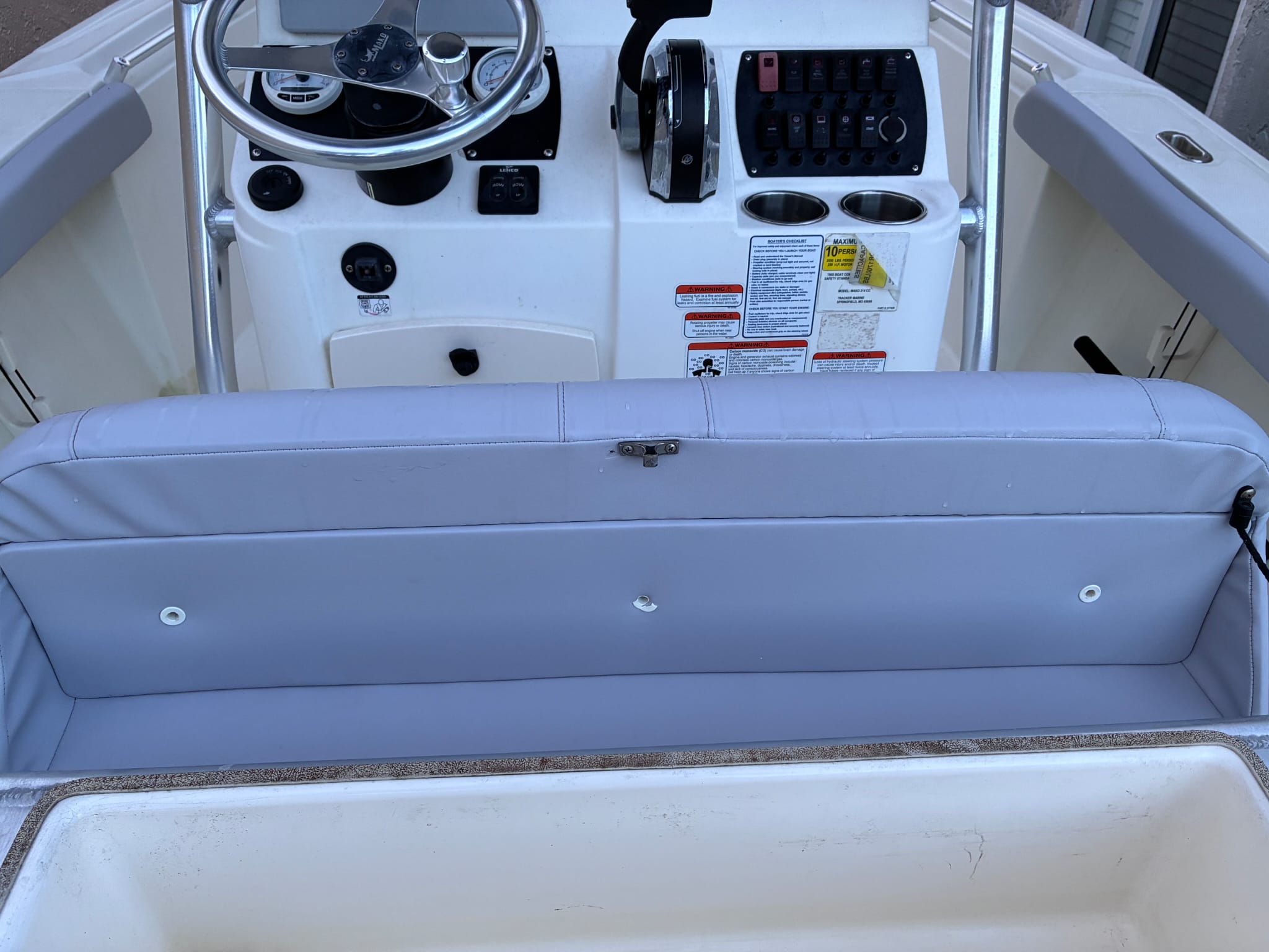 A boat's new gray vinyl helm seat cushion installed in front of the steering console and dash.