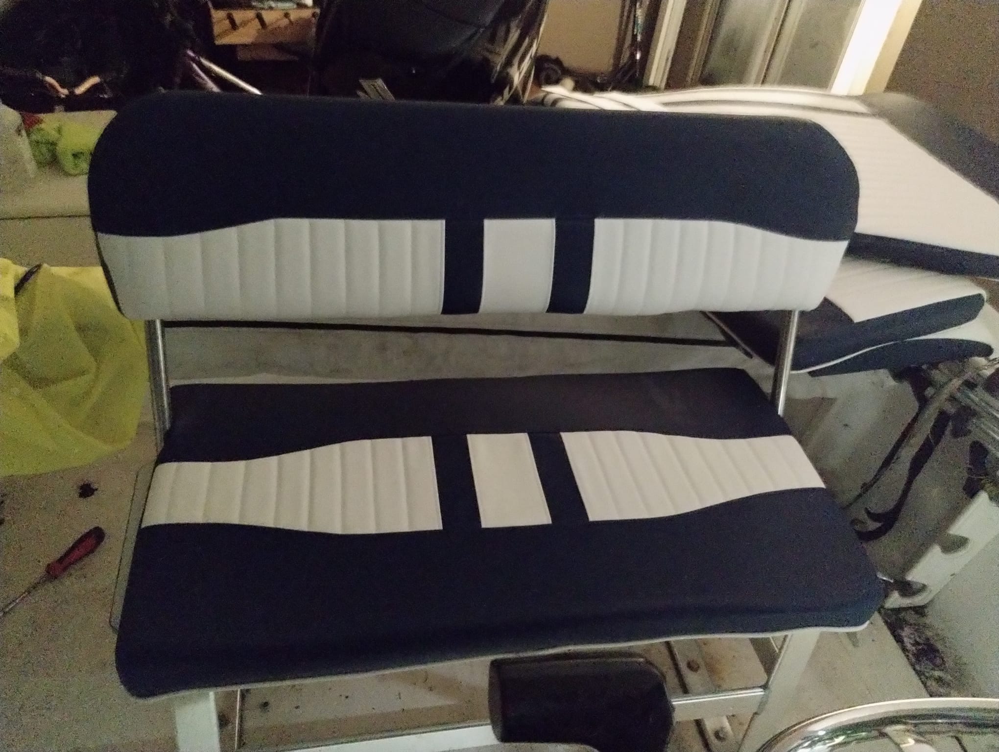Reupholstered boat bench seat in navy and white marine vinyl on the bench in the upholstery workshop