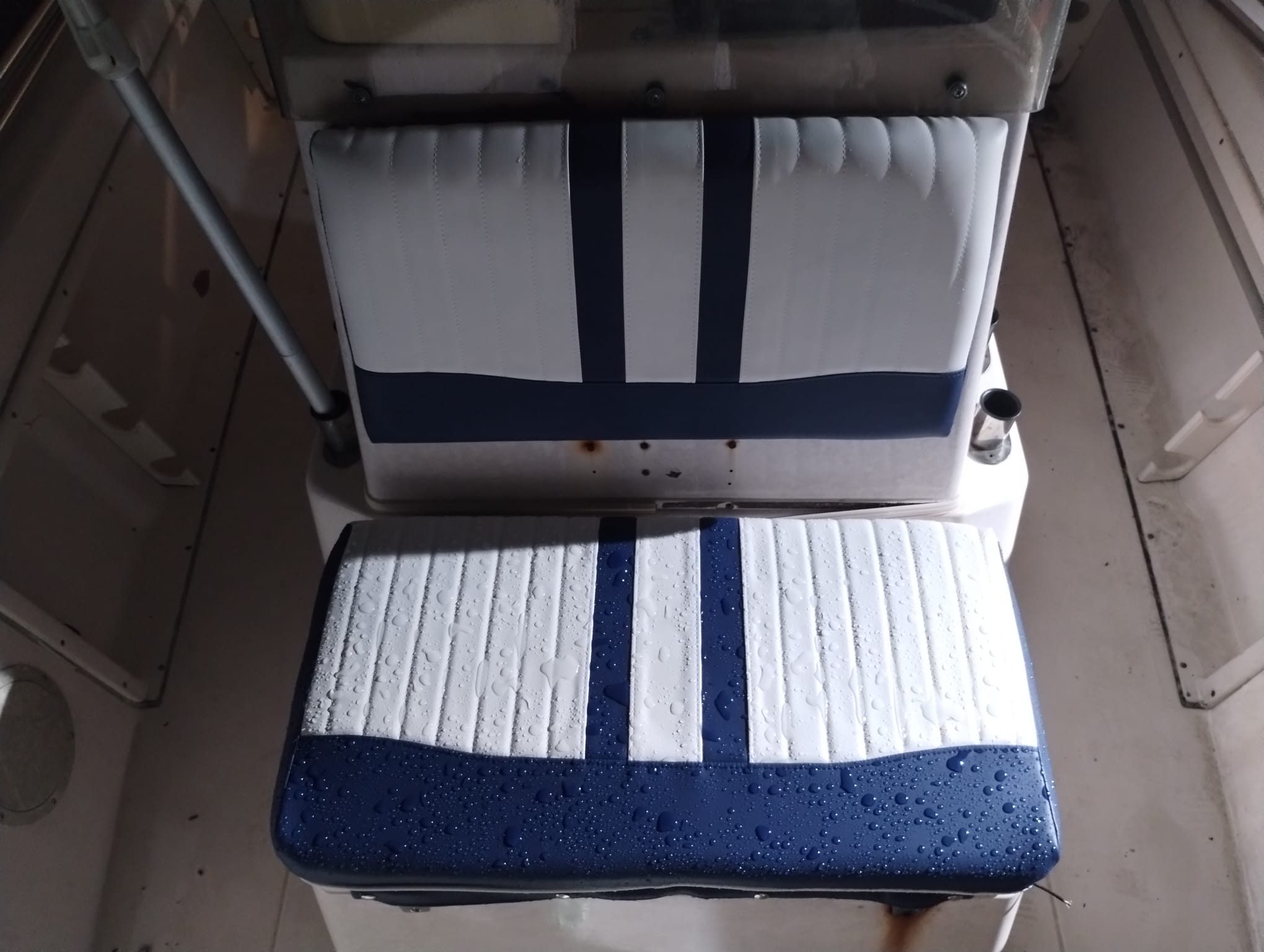 Newly reupholstered boat bench seat in white and navy marine vinyl installed in the boat