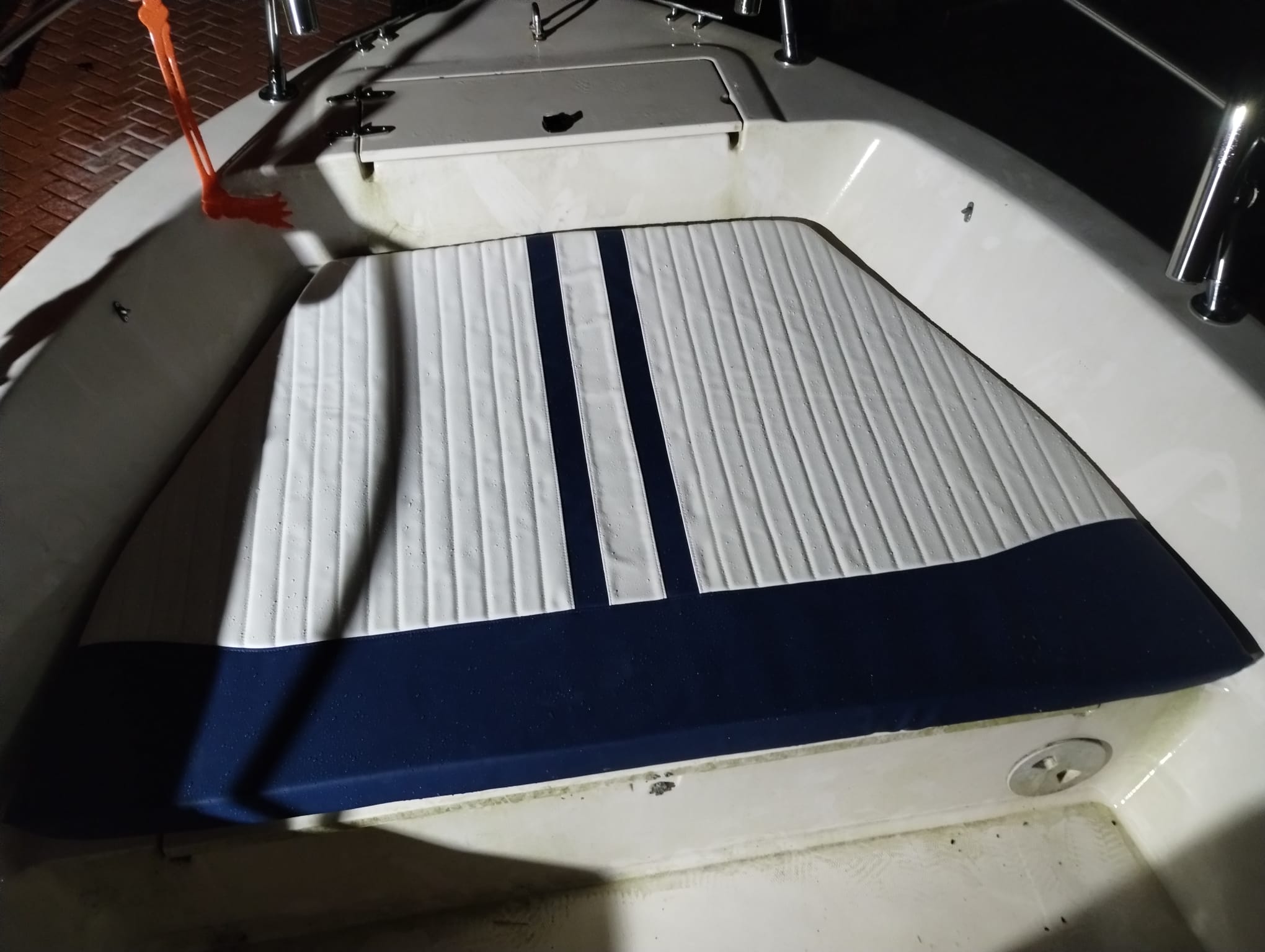 Newly reupholstered boat bow cushion in white and navy marine vinyl fitted in the bow